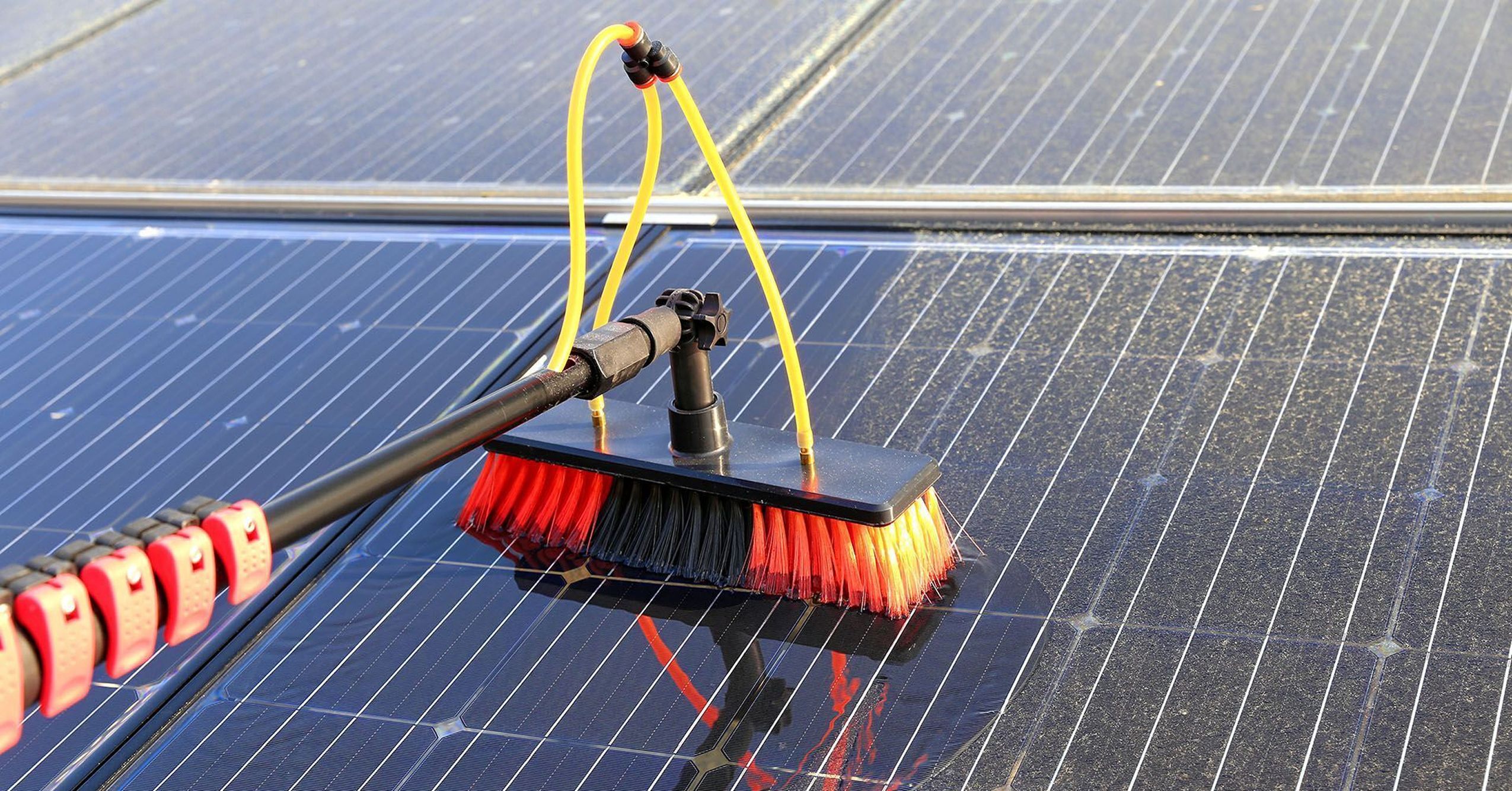 Spezialbürste mit gelbem Schlauch reinigt eine Photovoltaikanlage